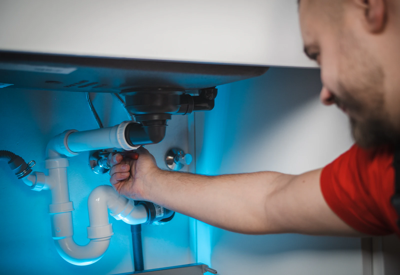 Plumber repairing pipes beneath a sink